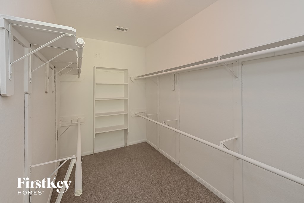 a large walk in closet in a white room with white shelves and a white wardrobe