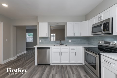 A kitchen with white cabinets and a wooden floor.