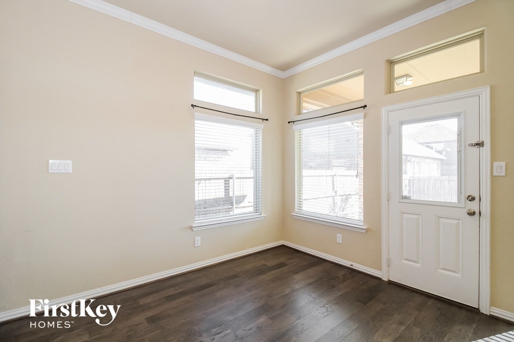 the living room of a home with wood flooring and three windows