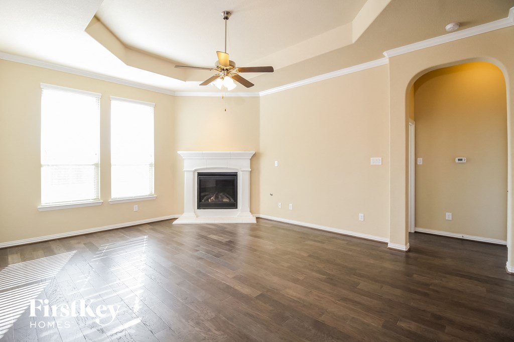 an empty living room with a fireplace and a ceiling fan