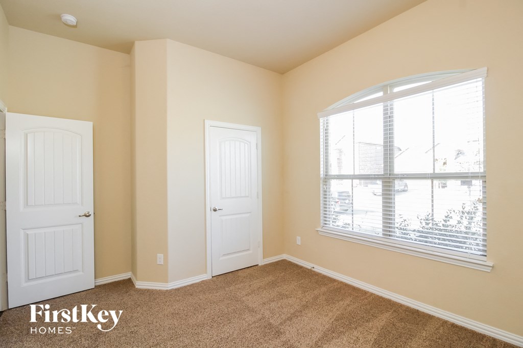 a bedroom with a window and two doors and a carpeted floor