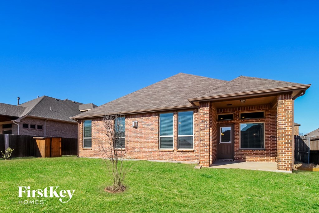 a brick house with a porch and a grass yard