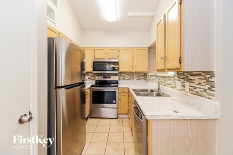 A kitchen with a stainless steel refrigerator and wooden cabinets.