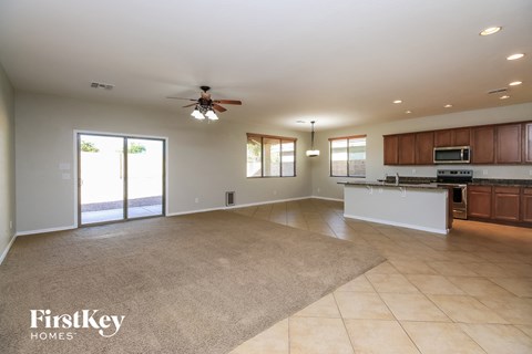 A spacious living room with a kitchen area in the background.