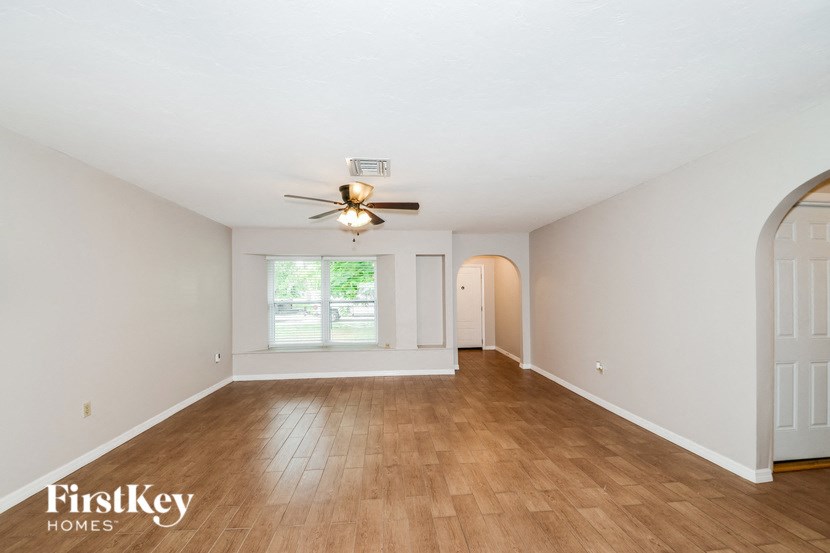 an empty living room with a ceiling fan and a window
