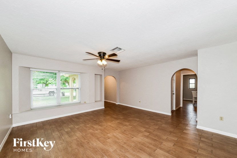 an empty living room with a ceiling fan and wood floors
