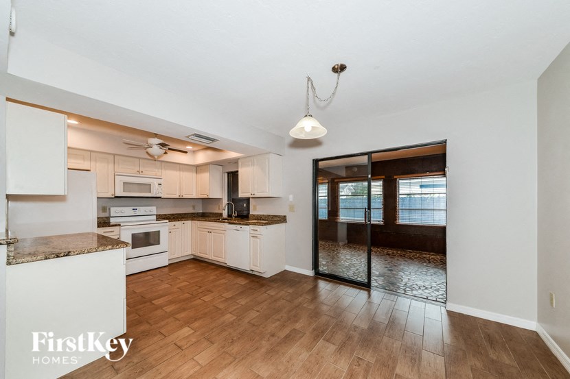 an empty kitchen with white cabinets and a wood floor