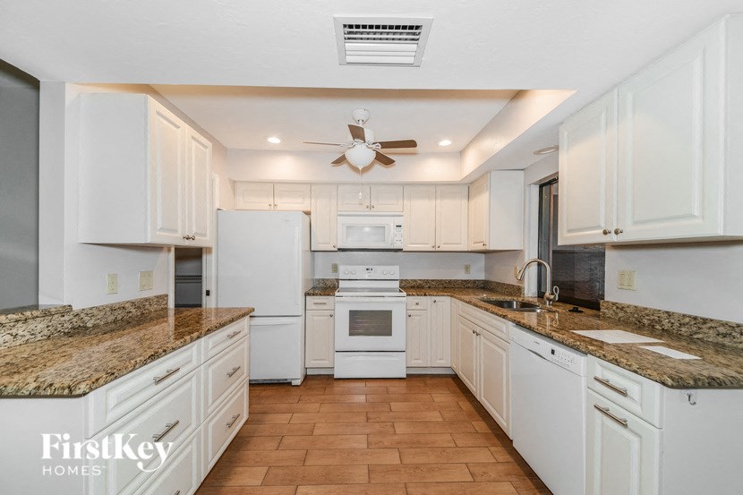 a kitchen with white cabinets and marble counter tops