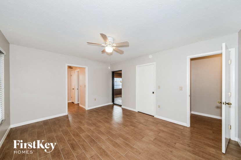 an empty living room with a ceiling fan and wood flooring