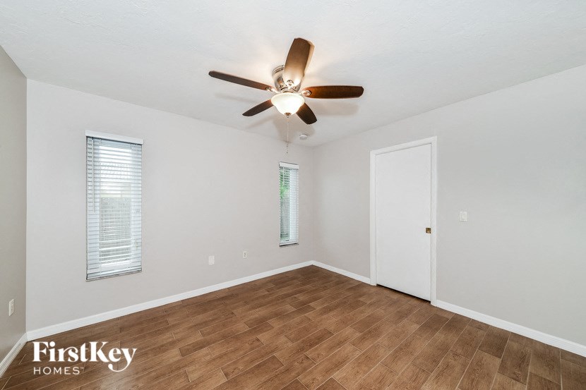 an empty living room with a ceiling fan and wood flooring
