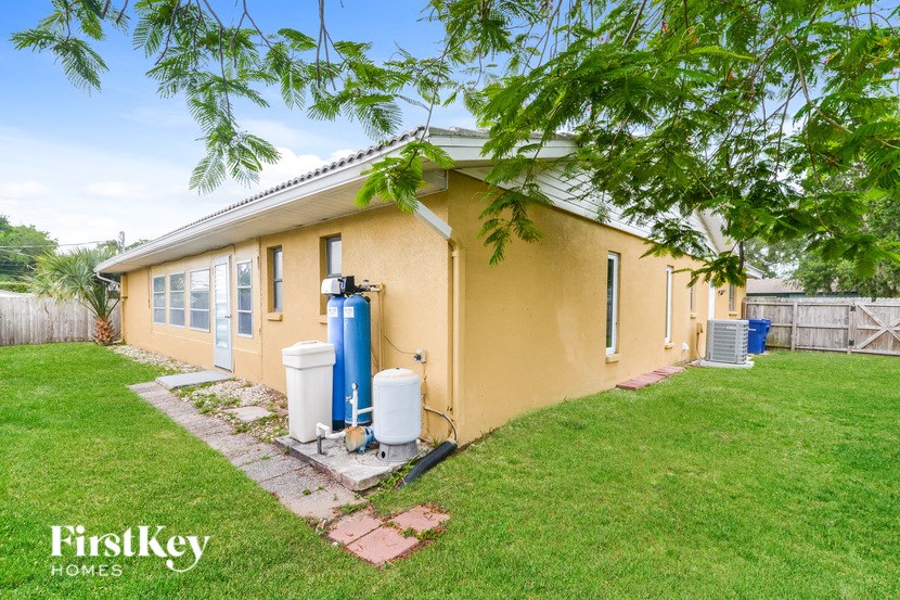 a small yellow house with a yard and a blue water pump