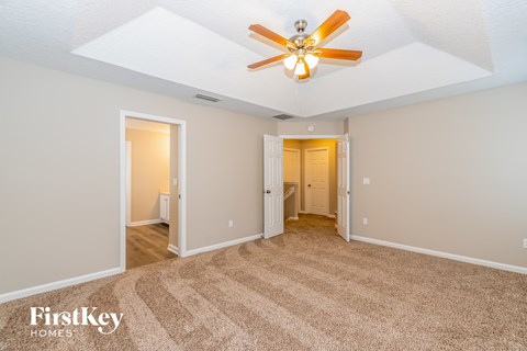 a living room with a ceiling fan and a carpet