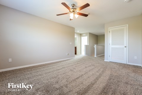 a spacious living room with carpet and a ceiling fan