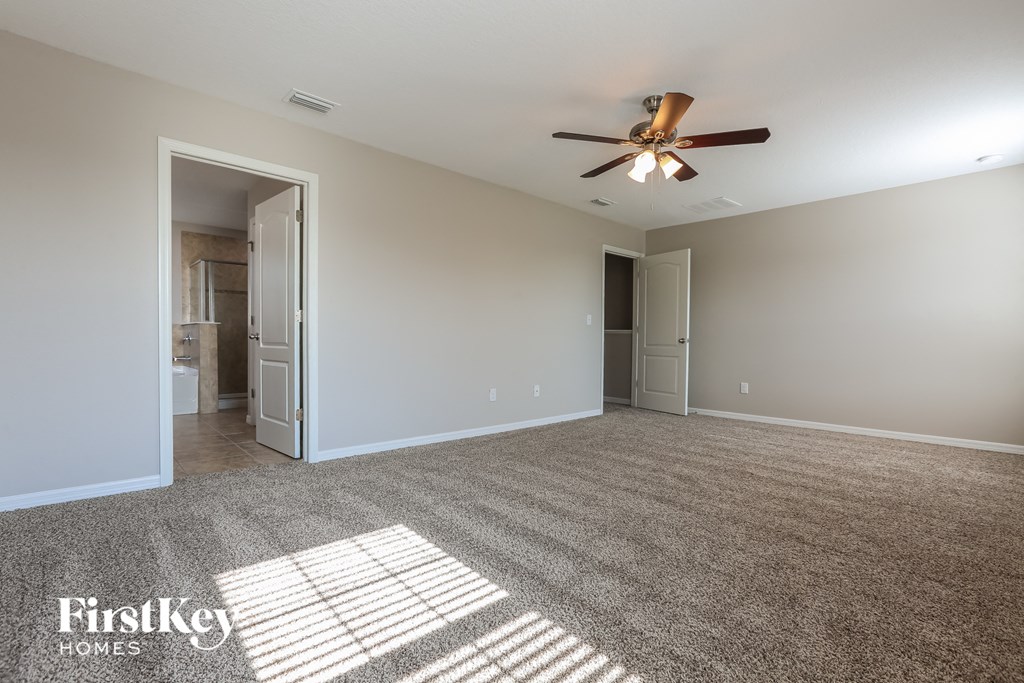 a spacious living room with carpet and a ceiling fan