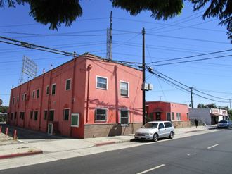 a red building on the corner of a street with a car