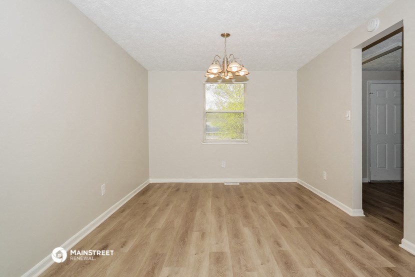 the spacious living room with hardwood flooring and a window