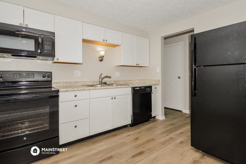 a kitchen with white cabinets and black appliances and a refrigerator