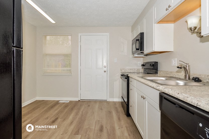 a kitchen with white cabinets and a sink and a refrigerator