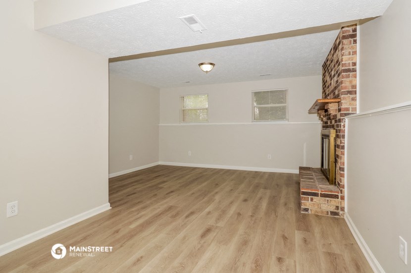 the living room of an empty house with wood flooring and a fireplace