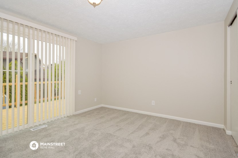 the spacious living room of a manufactured home with white walls and a sliding glass door