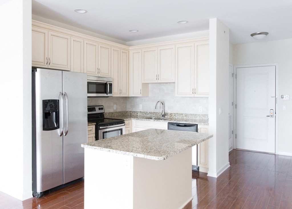 a kitchen with white cabinets and a marble counter top
