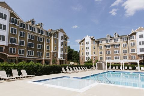a swimming pool with chairs in front of an apartment building