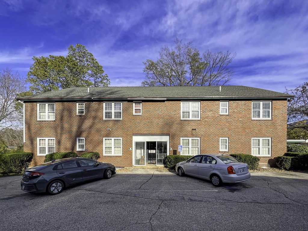 a brick apartment building with two cars parked in front