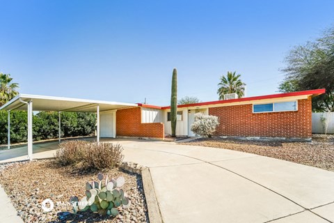 a house with a driveway and a cactus in front of it