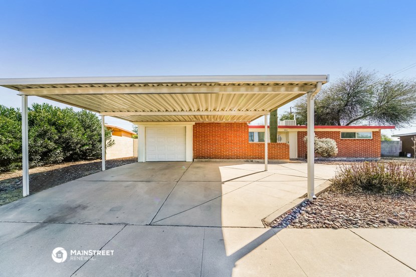a covered parking lot in front of a brick building with a white garage door