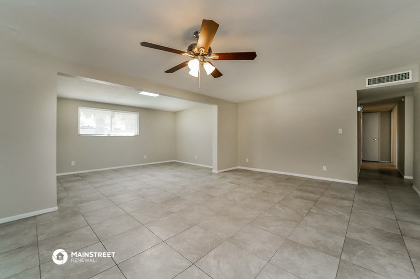 the empty living room with ceiling fan and tiled floor