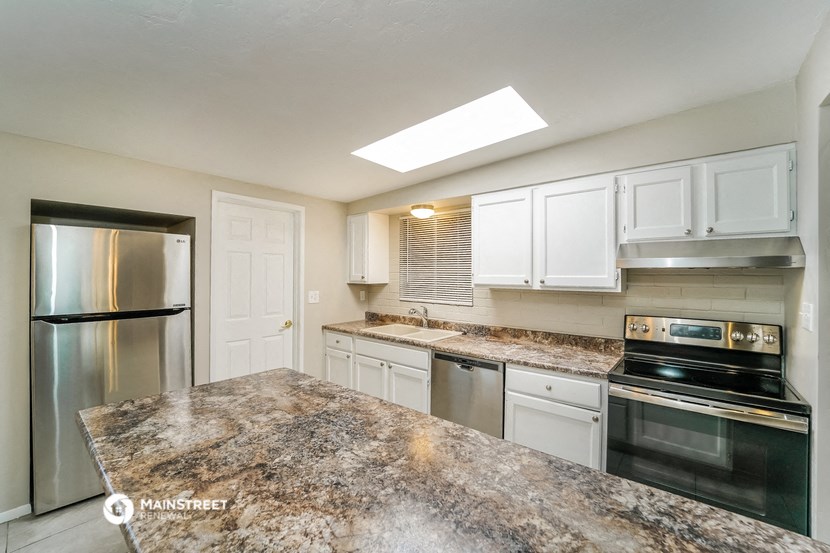 a kitchen with white cabinets and granite counter tops and stainless steel appliances
