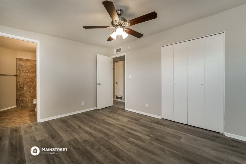 a bedroom with white walls and a ceiling fan