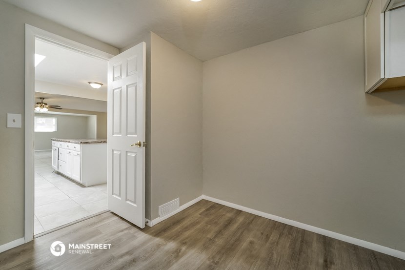 an empty living room and kitchen with a white door