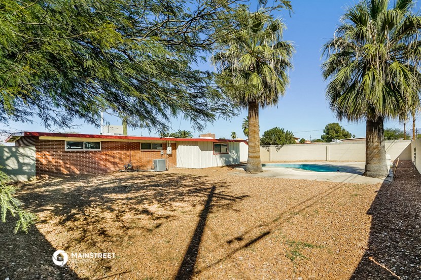 a small brick house with a pool and palm trees