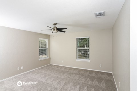 the spacious living room with carpet and a ceiling fan