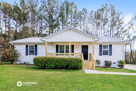a small white house with blue shutters and a lawn