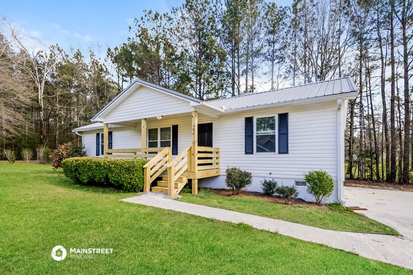 a small white house with a porch and a porch swing