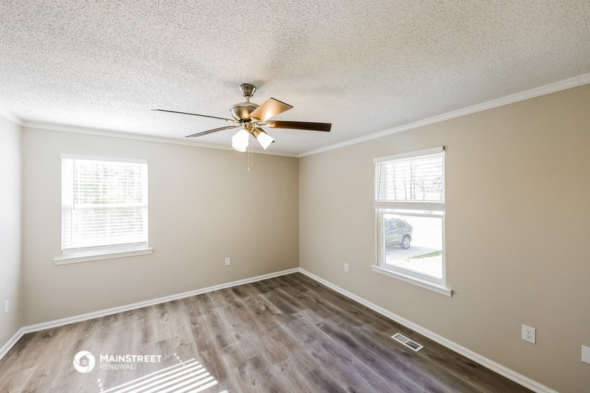 the spacious living room with ceiling fan and wood flooring