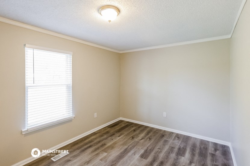 the spacious living room with wood flooring and a large window