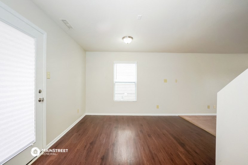 the living room of a home with wood floors and white walls