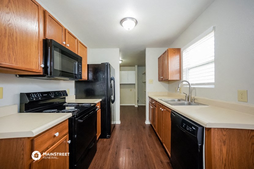 a kitchen with wood cabinets and black appliances and white counter tops