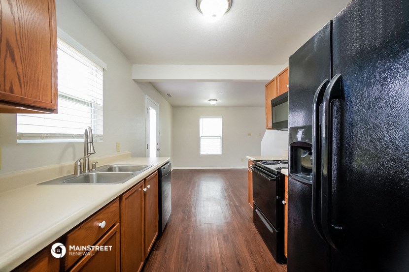 a kitchen with black appliances and white counter tops and wooden floors