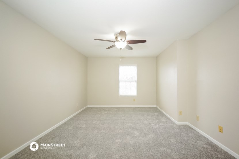 an empty room with a ceiling fan and a window