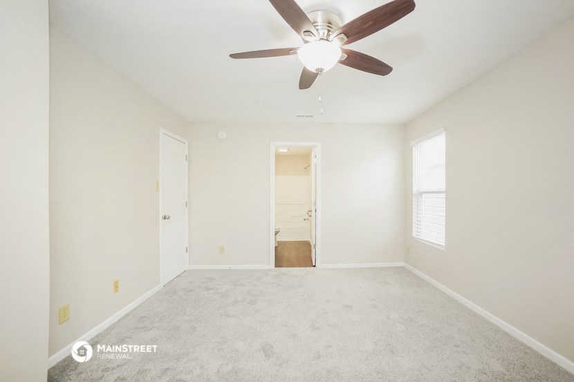 an empty living room with a ceiling fan and white walls