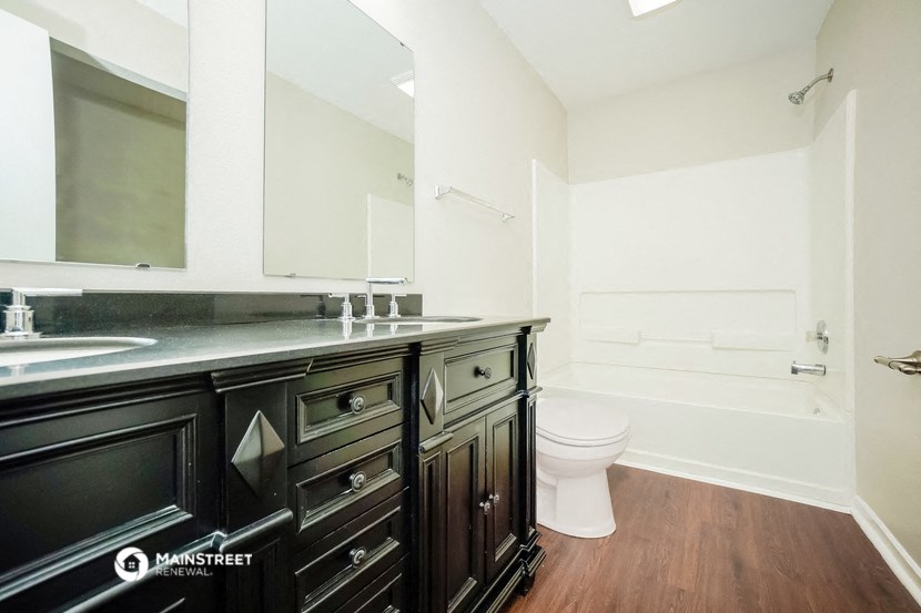 a bathroom with a large mirror and a sink and a toilet