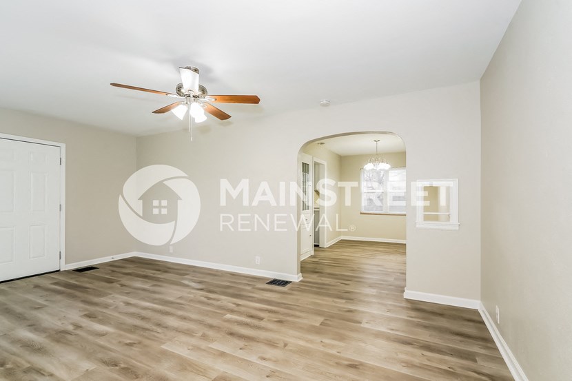 a renovated living room with hardwood floors and a ceiling fan
