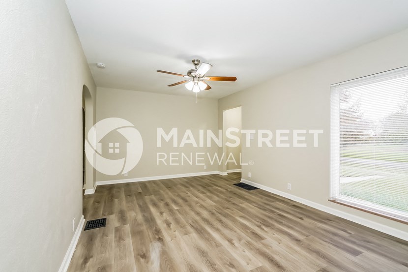 a renovated living room with hardwood floors and a ceiling fan