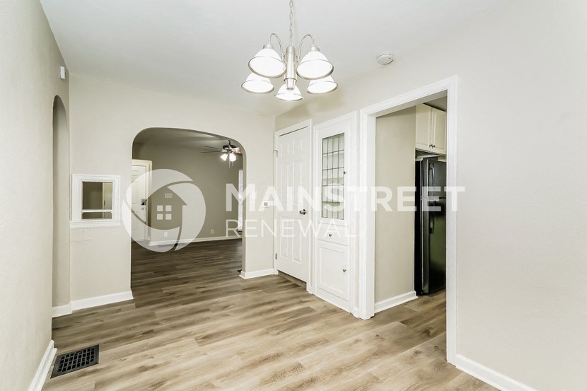 a renovated living room and hallway with white walls and wood floors