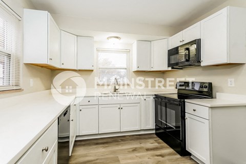 a white kitchen with white cabinets and black appliances