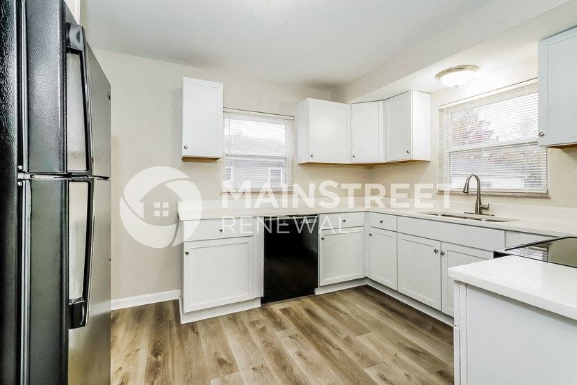 a white kitchen with white cabinets and a black refrigerator